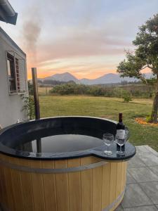 a hot tub with a bottle of wine and two glasses at Tulbagh Tiny Homes in Tulbagh