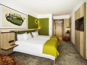 a hotel room with a large white bed and green walls at Mercure Katowice Centrum in Katowice