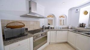 a kitchen with white cabinets and a sink and a microwave at ZenBreak Sugar Breeze B106 2bd in Saint James