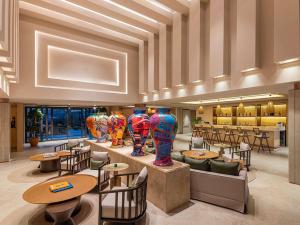 eine Lobby mit Tischen, Stühlen und Vasen in der Unterkunft The Bodrum Hotel Yalıkavak - MGallery Collection in Yalıkavak