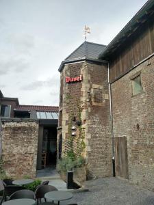 un bâtiment en briques avec un panneau d'église sur celui-ci dans l'établissement de Twie Keuninge, à Maasmechelen