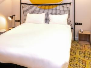- une chambre avec un grand lit blanc et une tête de lit jaune dans l'établissement Greet Boulogne Billancourt Paris, à Boulogne-Billancourt