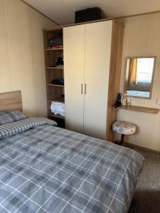 a bedroom with a bed and a cabinet and a window at Steph's Haven in Skipsea