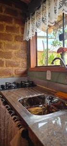 a kitchen counter with a sink and a window at CHALEZINHO Da LÚ in Carrancas