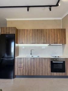 a kitchen with a black refrigerator and wooden cabinets at Nest Studio in Katerini