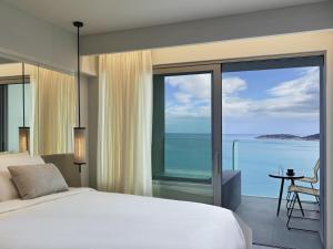 a bedroom with a bed and a view of the ocean at NIKO Seaside Resort MGallery in Agios Nikolaos