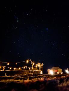 a starry sky at night with a building and lights at Infinity sahara camp in Merzouga
