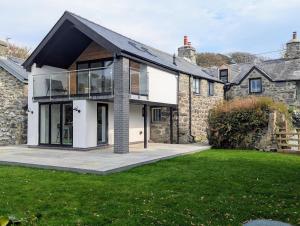 an old stone house with a black roof at Ty Isaf Welsh Farmhouse with Sea Views in Llanddwywe