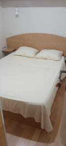 Elle comprend un grand lit avec des draps et des oreillers blancs. dans l'établissement Family mobile home solar powered near the sea and the airport, à Áyios Spirídhon