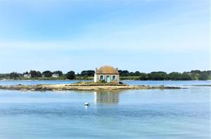 an island with a house in the middle of the water at Studio calme in Merlevenez
