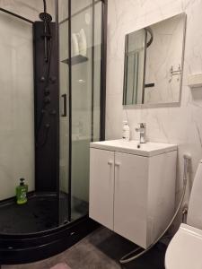 a bathroom with a white sink and a shower at Nordstay Tromso in Tromsø +2 photos