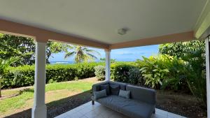 a couch on a porch with a view of the ocean at Malora Beach in Le Moule