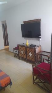 a living room with a flat screen tv on a cabinet at Perto do peixe Marley - Praia do Morro in Guarapari +4 photos