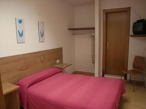 a bedroom with a bed with a pink blanket at Hostal Caracas in Lalín