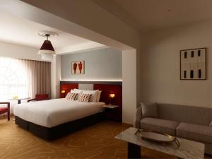 Un dormitorio con una cama grande y un sofá. en Hotel Morris Sydney, Handwritten Collection, en Sídney