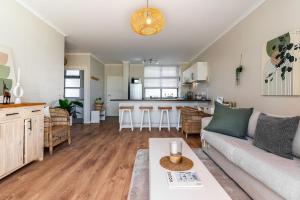 a living room with a couch and a kitchen at Melrose Tide 1 Bed Spacious Apartment in Muizenberg