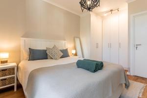 a bedroom with a large white bed with blue pillows at Melrose Tide 1 Bed Spacious Apartment in Muizenberg +12 photos