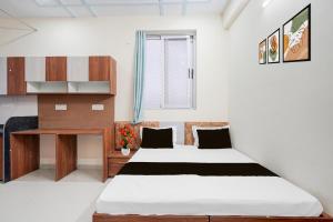 a bedroom with a bed and a desk in it at Hotel O Radha Residency in Dahmi