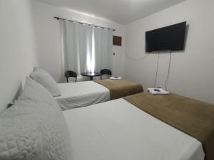a hotel room with two beds and a flat screen tv at Pousada Jardins in Macaé