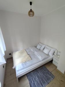 a white bed in a white room with a rug at Modrzewiowy Zakątek in Ołobok +51 photos