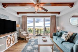 a living room with a couch and a flat screen tv at Ocean Song 324 in Tybee Island