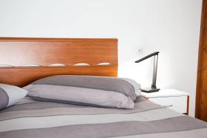 1 cama con cabecero de madera y una lámpara sobre una mesa en Casa Liscidini, en Aprica
