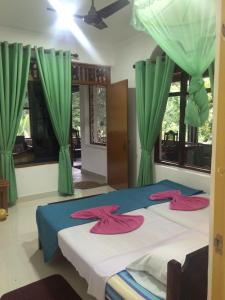 1 dormitorio con 2 camas y cortinas verdes en Green Woods, en Kandy