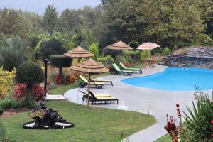 a swimming pool with chairs and umbrellas next to at Sonho Verde in Ribeira de Pena