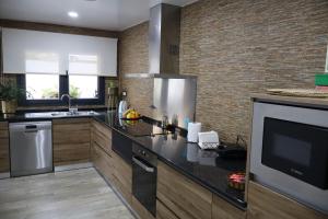a kitchen with black counter tops and a television at Sonho Verde in Ribeira de Pena