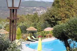 a swimming pool with a yellow umbrella and chairs and umbrellas at Sonho Verde in Ribeira de Pena