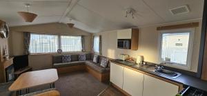 a kitchen and living room with a couch and a table at South Breeze Caravans in Camber