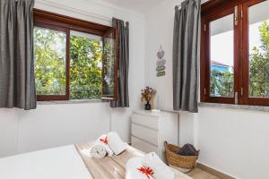 a bedroom with two windows and a bed with towels at Casa das Laranjeiras in Alfarim