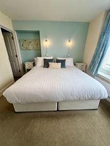 a bedroom with a large white bed with blue walls at The Wayfarer Inn in Instow