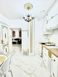 a kitchen with white cabinets and a chandelier at Apartament Królewski in Gniezno +10 photos