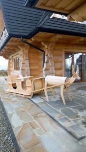 a log cabin with a bench and a deer statue at Bachledowy Wierch in Czerwienne