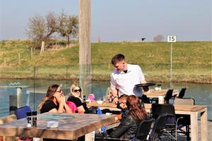 een man die aan tafels staat voor een groep mensen bij Tiny Boat House #4 in Garnwerd