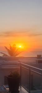 a sunset on the beach with a plant on a balcony at Sunseaker- Beachfront Complex in Ballito +12 photos