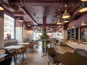 un restaurant avec des tables, des chaises et des lampes suspendues dans l'établissement Aparthotel Adagio Malta Central, à Msida