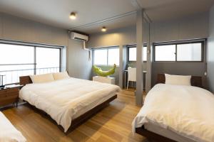 two beds in a bedroom with windows and a table at 博多町家小箱 in Fukuoka