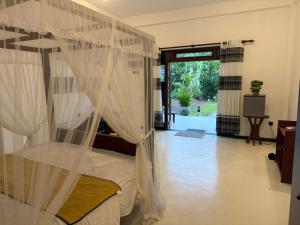 a bedroom with a bed with mosquito netting at Natural Lake Down South in Habaraduwa