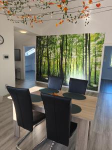 a dining room with a table and chairs with a forest mural at Waldzauber - Moderne Ferienwohnung im Grünen in Elpenrod