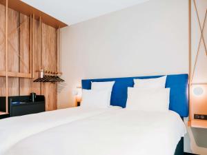 a bedroom with a large white bed with a blue headboard at Mercure Brest Centre Port in Brest +41 photos