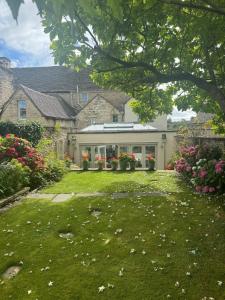 a yard with flowers in front of a house at Vine House in Tetbury