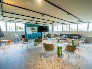 a room with chairs and tables and a tv at Greet hôtel Montpellier Aéroport Parc des Expos in Mauguio