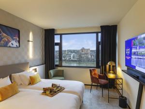 a hotel room with a bed and a flat screen tv at Mercure Namur Hotel in Namur