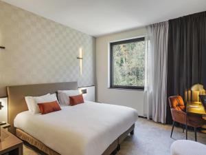 a hotel room with a large bed and a window at Mercure Namur Hotel in Namur
