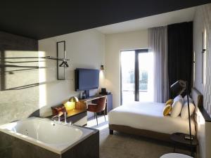 a bedroom with a tub and a bed and a television at Mercure Namur Hotel in Namur +151 photos