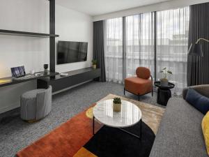 una sala de estar con un sofá y una silla en The Sebel Canberra Campbell, en Canberra