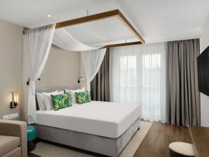 a bedroom with a large white bed and a couch at Mövenpick Balaland Resort Lake Balaton in Szántód +155 photos