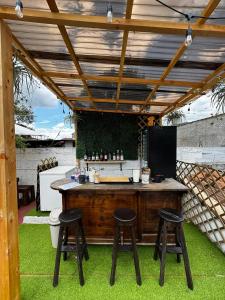 an outdoor bar with stools under a wooden pergola at Hotel Casa Nikté in Antigua Guatemala